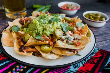 Mexican Nachos with cheese or tortilla chips with meat, avocado and beer, tex mex food in Mexico America