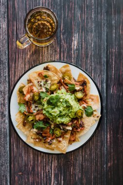 Mexican Nachos with cheese or tortilla chips with meat, avocado and beer, tex mex food in Mexico America