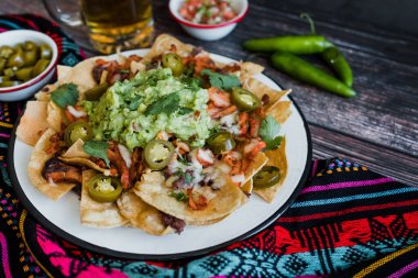 Mexican Nachos with cheese or tortilla chips with meat, avocado and beer, tex mex food in Mexico America