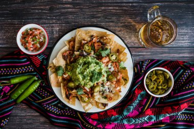 Mexican Nachos with cheese or tortilla chips with meat, avocado and beer, tex mex food in Mexico America