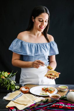 Mexican woman preparing tacos al pastor and eating mexican food in Mexico Latin America clipart