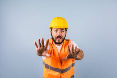 portrait of Hispanic bearded young man engineering and worker with hard helmet in Mexico Latin America on blue background