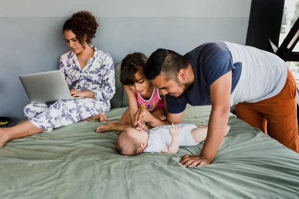 Happy hispanic family laughing and having fun together on the bed at home in Mexico Latin America