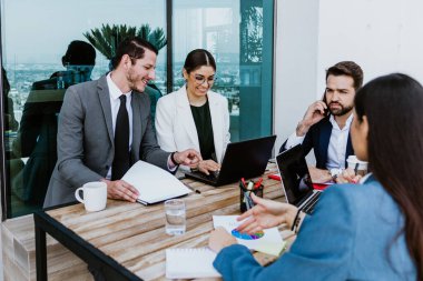 Group of hispanic business people in a informal meeting using laptop on the terrace of the office in Mexico Latin America, teamwork working