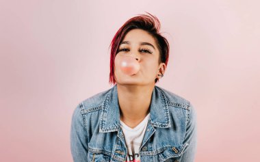 Portrait of hispanic young woman with colored hair chewing gum and headphones listening music in Mexico Latin America