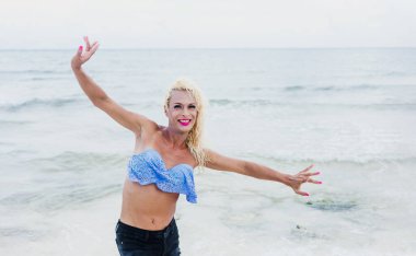 Meksika 'da Latin Amerika plajında makyaj yapan ve kadın kıyafeti giyen genç bir transseksüel.