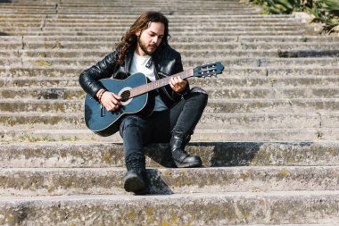 Rock 'n' roll tarzında Latin Amerika 'da sokakta gitar çalan genç İspanyol bir adam.