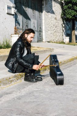 Rock 'n' roll tarzında genç İspanyol bir adam ve Meksika Latin Amerika 'da sokaklarda bagetlerle gitar çalıyor.