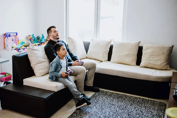 Latin father and his son playing video games and competing with each other at home in Mexico, Hispanic people