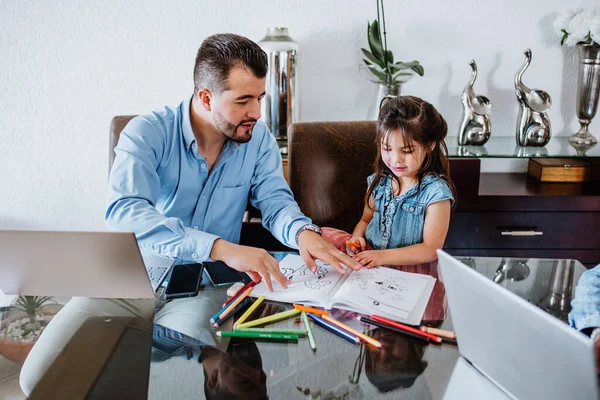 Latin father help cheerful little daughter with school homework and using computer at home in Mexico, hispanic family