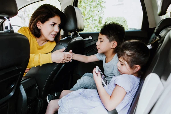 Latin mother with children daughter and son in her car ready to travel in Mexico, Hispanic family
