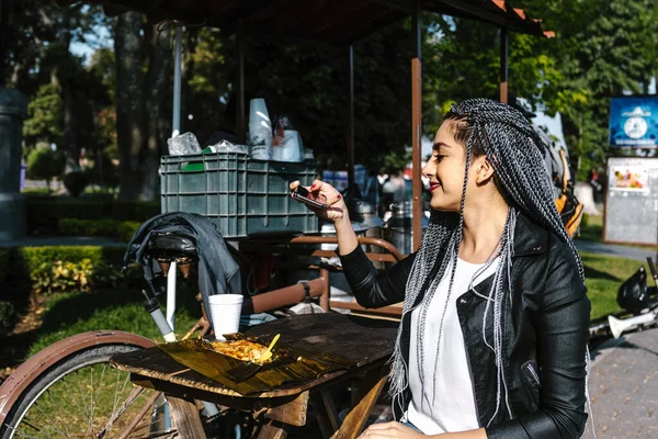 young latin woman with braids hair eating mexican tamales street food on park in Mexico city, hispanic people