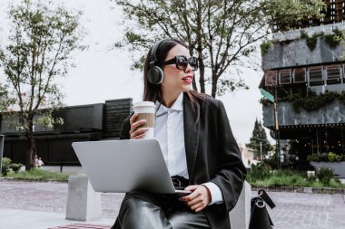 Latin Amerika 'da Mexico City' de dizüstü bilgisayar ve kulaklık kullanan Latin bir iş kadını. Latin bir kadın.