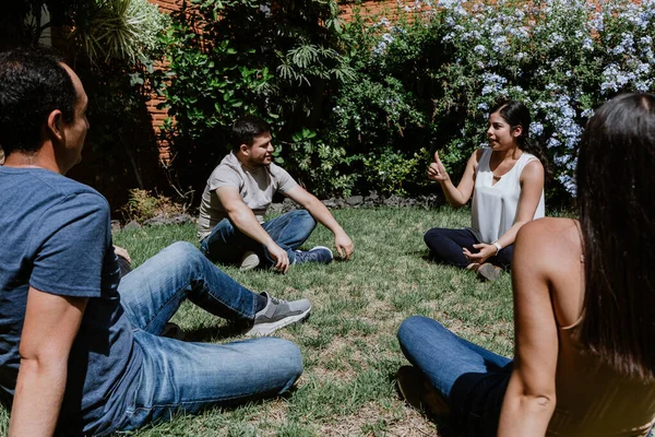 hispanic young people seated in circle on grass and participating at group therapy session in Mexico Latin America