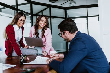 Latin iş dünyasından genç insanlar Meksika 'daki ofiste bilgisayar ya da dizüstü bilgisayar kullanıyor ya da çalışıyor.
