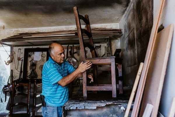 Latin kıdemli marangoz, Meksika Latin Amerika 'daki mobilya atölyesinde ahşap sandalyede çalışıyor.