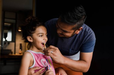 Latin genç bir baba kızına Meksika 'da dişlerini nasıl fırçalayacağını öğretiyor.