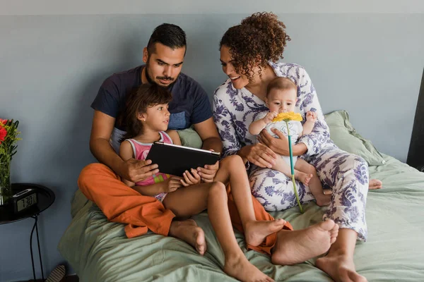 latin family watching a movie on digital tablet together on bed at home in Mexico Latin America, hispanic people