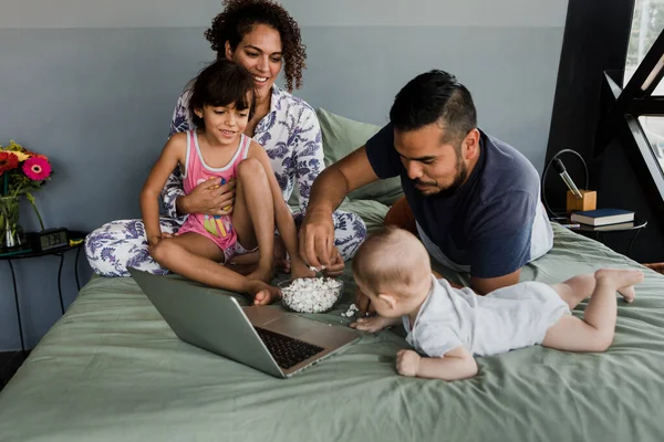 latin family watching a movie on laptop computer together on bed at home in Mexico Latin America, hispanic people
