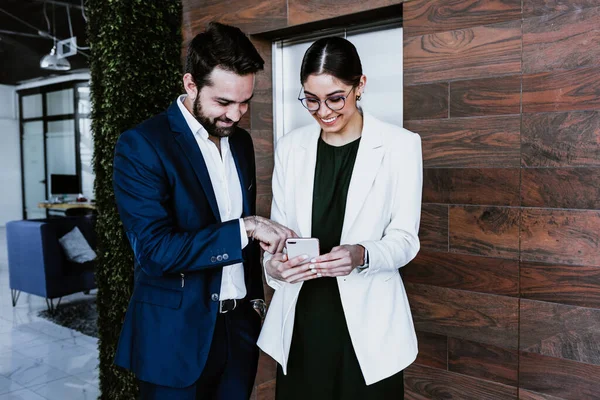 stock image young hispanic couple of coworkers woman and man at work using mobile phone at office in Mexico Latin America, hispanic people