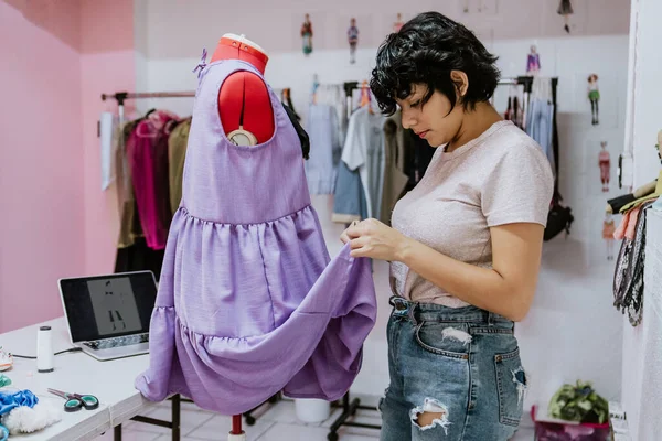 young latin woman fashion designer working with mannequins and colorful fabrics at fashion workshop in Mexico Latin America