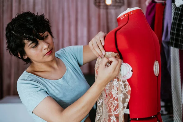 young latin woman fashion designer working with mannequins and colorful fabrics at fashion workshop in Mexico Latin America
