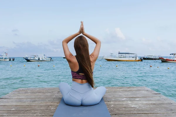 Young latin woman practicing yoga on the beach pier or dock at the seaside in Mexico Latin America, hispanic people