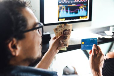 Finansal Adam, Meksika Latin Amerika 'da bilgisayarla çevrimiçi alışveriş yapmak için kredi kartı tutuyor.
