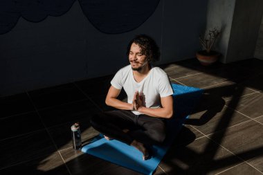 Latin kökenli genç bir adam, Meksika 'da Latin Amerika' da dizüstü bilgisayarında yoga ve spor yapıyor.