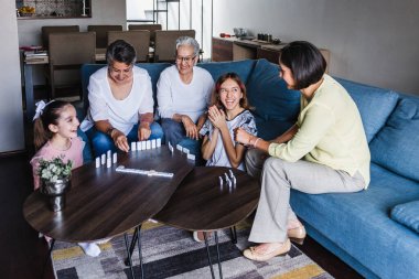 Latin aile evde büyükanne ve kızıyla domino oynuyor. Üç nesil boyunca Latin Amerika 'da Latin kökenli kadınlar var.