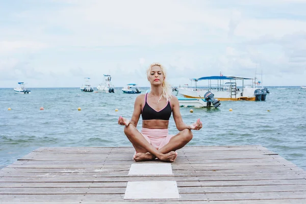 Young Transgender latin woman meditating on the beach pier or dock at the seaside in Mexico Latin America, hispanic lgbt community