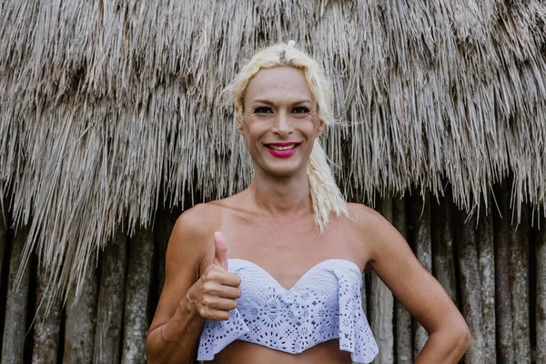 Young transgender latin woman with thumbs up and copy space at the beach in Mexico Latin America, hispanic lgbt community