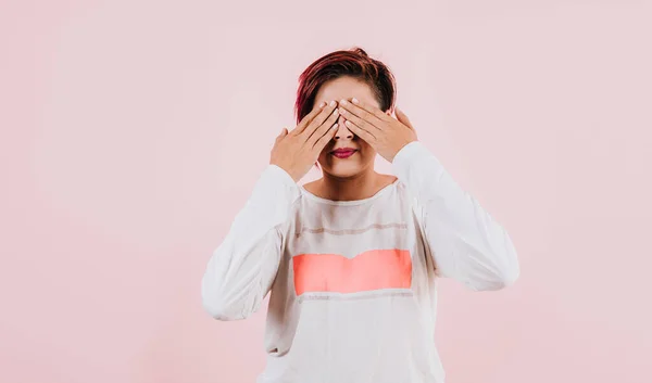 portrait of young latin woman with face expressions and closed eyes on coral pink background in Mexico Latin America, hispanic people
