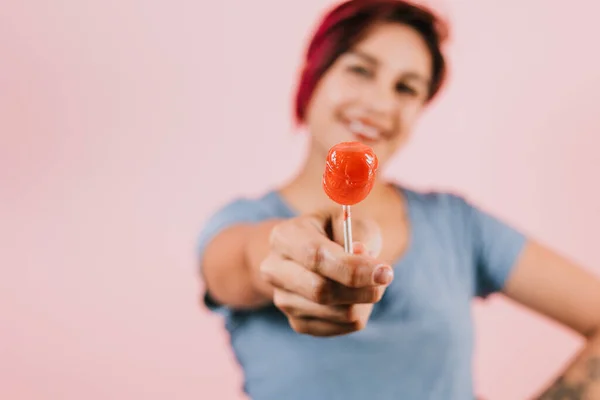 young latin woman licking a red lollipop on pink coral background in Mexico Latin America, hispanic people