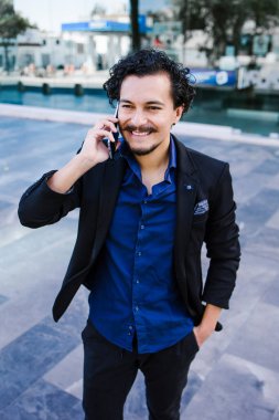 Latin Amerika 'da Latin kökenli genç bir adam Meksika' da sokakta cep telefonuyla konuşuyor.