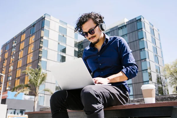 young latin man using laptop and working on in bench in Mexico city Latin America, hispanic people