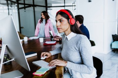 Latin Amerika 'daki ofiste bilgisayar ya da dizüstü bilgisayar kullanan genç Latin iş kadını Latin takım çalışması yapıyor.
