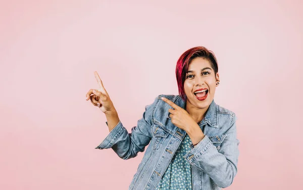 young latin woman with pointing finger to copy space in casual clothes on pink coral studio background in Mexico Latin America, hispanic female