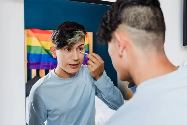 stock image Young latin homosexual man applying makeup with mirror in bedroom at home in Mexico, Hispanic homosexual and lgbtq community in Latin America