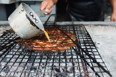 Meksika usulü ızgara balık yapan Meksikalı adamın elleri ya da Pescado a la Talla adında ızgara balık.