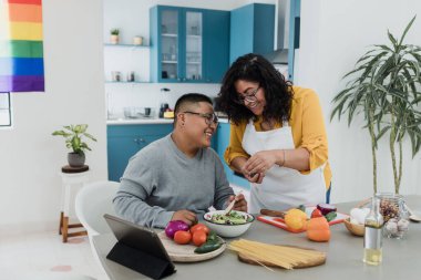 Latin lezbiyen çift Meksika 'da mutfakta yemek pişiriyor. Latin Amerika' da gökkuşağı bayrağı taşıyan, LGBT topluluğundan homoseksüel İspanyol insanlar.