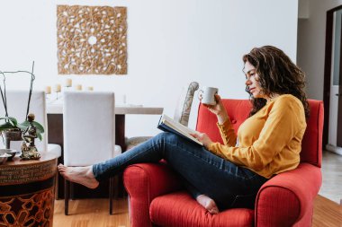 Latin yetişkin kadın kitap okuyor ve Meksika 'da evinde kanepede dinleniyor, Latin Amerika' da İspanyol kadın.