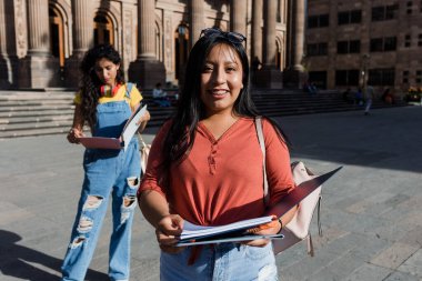 Latin Amerika 'daki genç Latin kadın üniversite öğrencisinin portresi, elinde kitap tutan İspanyol kız.