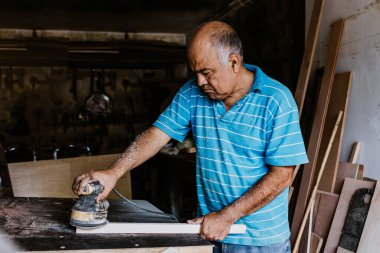 Latin kıdemli marangoz Meksika Latin Amerika 'daki marangozluk atölyesinde zımpara kağıdı kullanıyor ve çalışıyor.