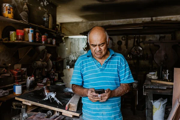 Latynoski Starszy Stolarz Korzystający Telefonu Pracujący Drewnem Warsztacie Stolarskim Meksyku — Zdjęcie stockowe