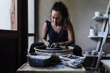 Latin kadın çömlekçinin elleri, Meksika Latin Amerika 'daki atölyesinde çömlek çarkının üzerinde kilden bir kap yaratıyor, İspanyol kadın.