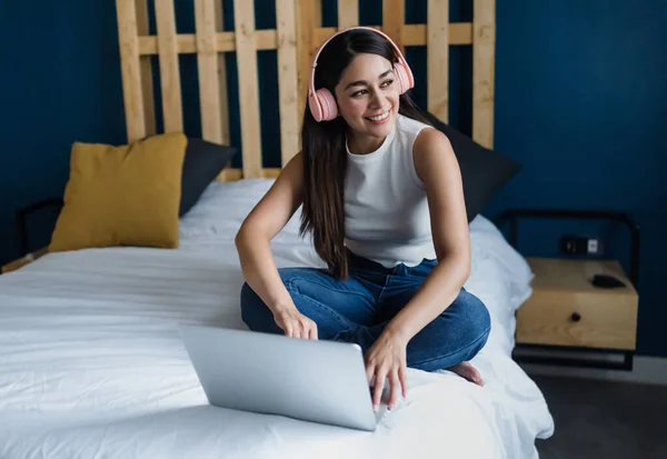 stock image young latin woman student using laptop and headphones in bed at home in Mexico Latin America, Hispanic people