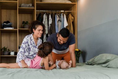 İki çocuklu Latin bir aile. Bebek ve kız. Meksika 'da, Latin Amerika' da, evde yatakta birlikte eğleniyorlar.