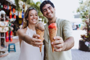 hispanic young couple eating ice cream on vacations or holidays in Mexico Latin America, Caribbean and tropical destination  clipart