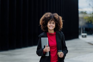 Latin Amerika 'da dizüstü bilgisayar tutan genç Afrikalı Amerikalı iş kadını, İspanyol finans ve Karayipliler 